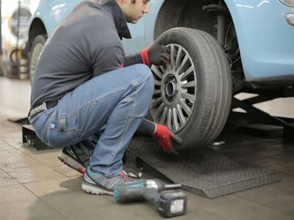 Mechanik zakłada koło na samochód osobowy